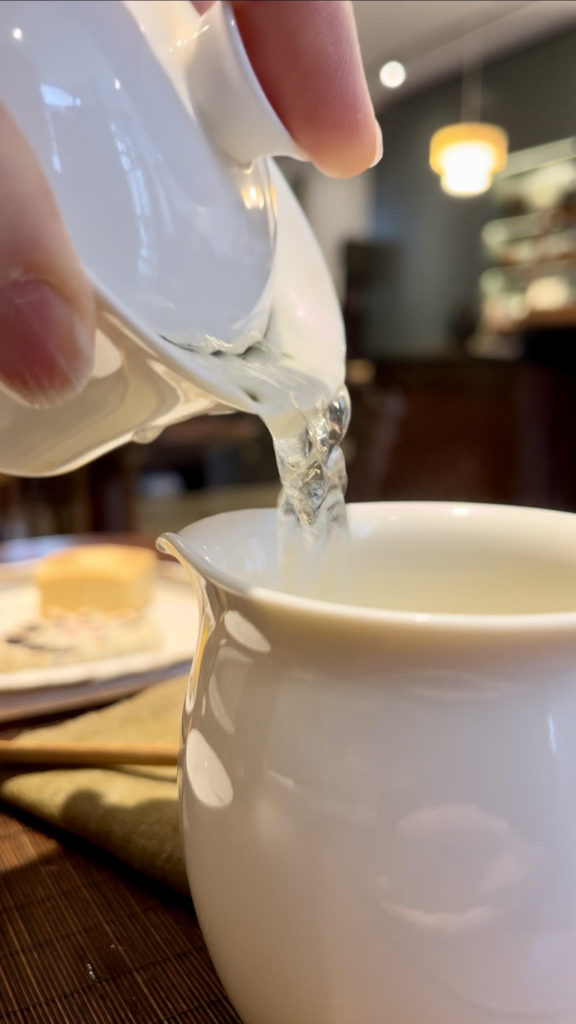 Pouring tea from white porcelain gaiwan to fairness pitcher at Wistaria Paris