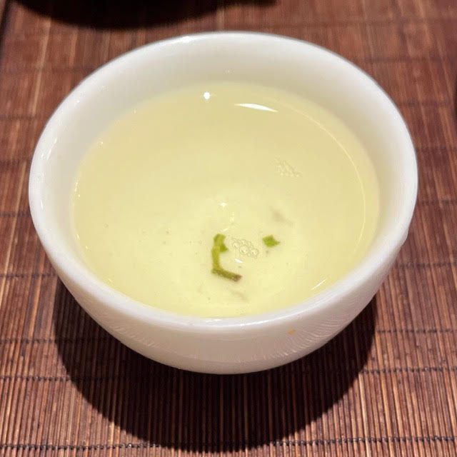 Infusion of Bi Luo Chun tea in a white teacup and containing a leaf fragment at Wistaria Paris Tea House