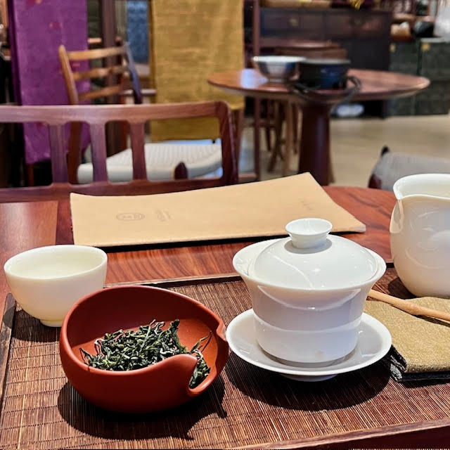 Gongfu set up with green tea leaves, white porcelain gaiwan, fairness pitcher, and cup at Wistaria Paris Tea House