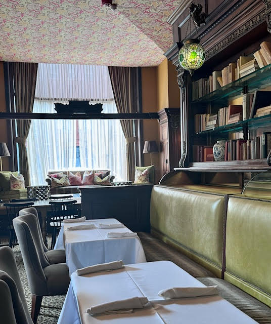 One view of part of the interior of Gryphon in Savannah, showcasing the moss green booths and mahogany bookshelves.