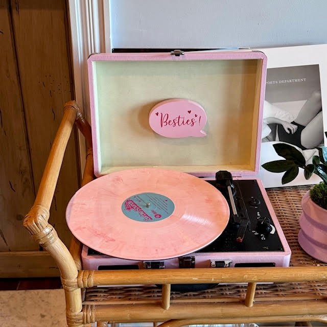 Pink suitcase record player that says "BesTea" inside the front lid and has a salmon-colored record.