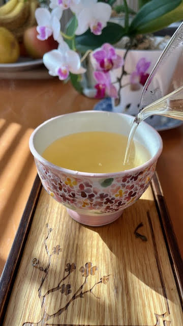 Tipsy Garden Barrel#2 golden yellow tea pouring from a glass pitcher into a floral teacup without a handle