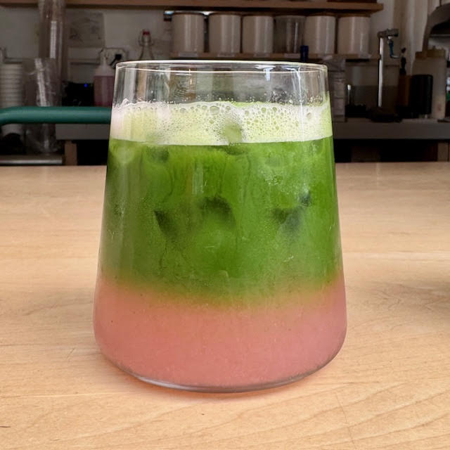 Iced Peach Matcha Shiso Soda in layers of green and peach in a glass sitting on the counter at Kettl's Bowery location in August 2024. 