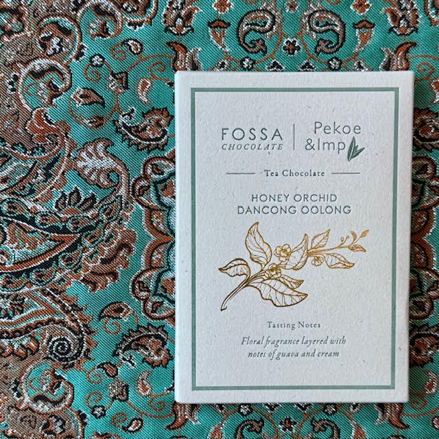 White packaging with green-blue writing of a Honey Dancong Oolong chocolate bar from Fossa Chocolate X Pekoe & Imp